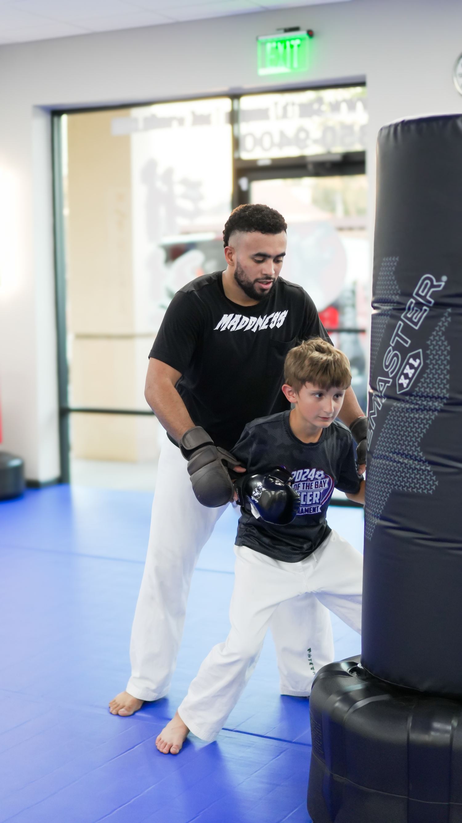 A coach working hands with a student on the bag at Traditional TaeKwon-Do Center